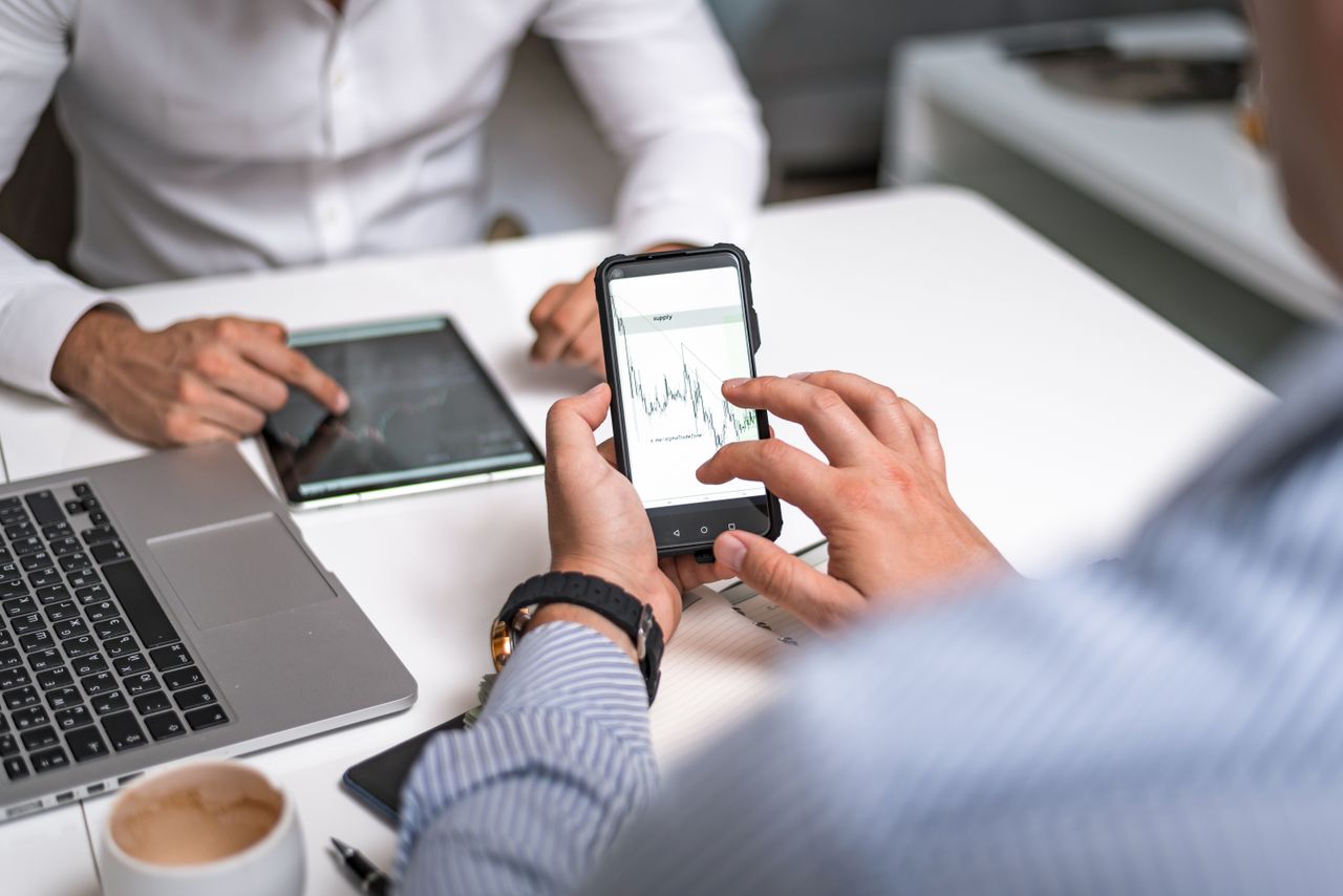 Two business professionals analyzing market trends on digital devices in an office setting.